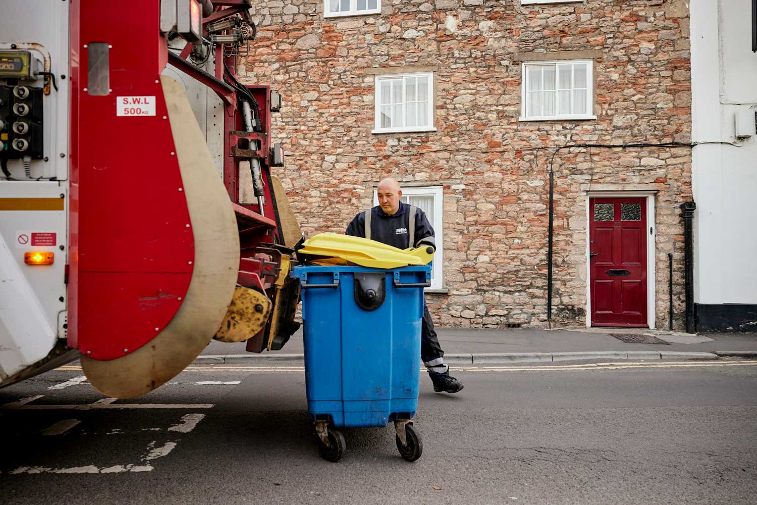 A JWitt Waste Recycling team member loading a wheelie bin on to the back of a lorry - JWitt Waste wheelie bin hire and collections
