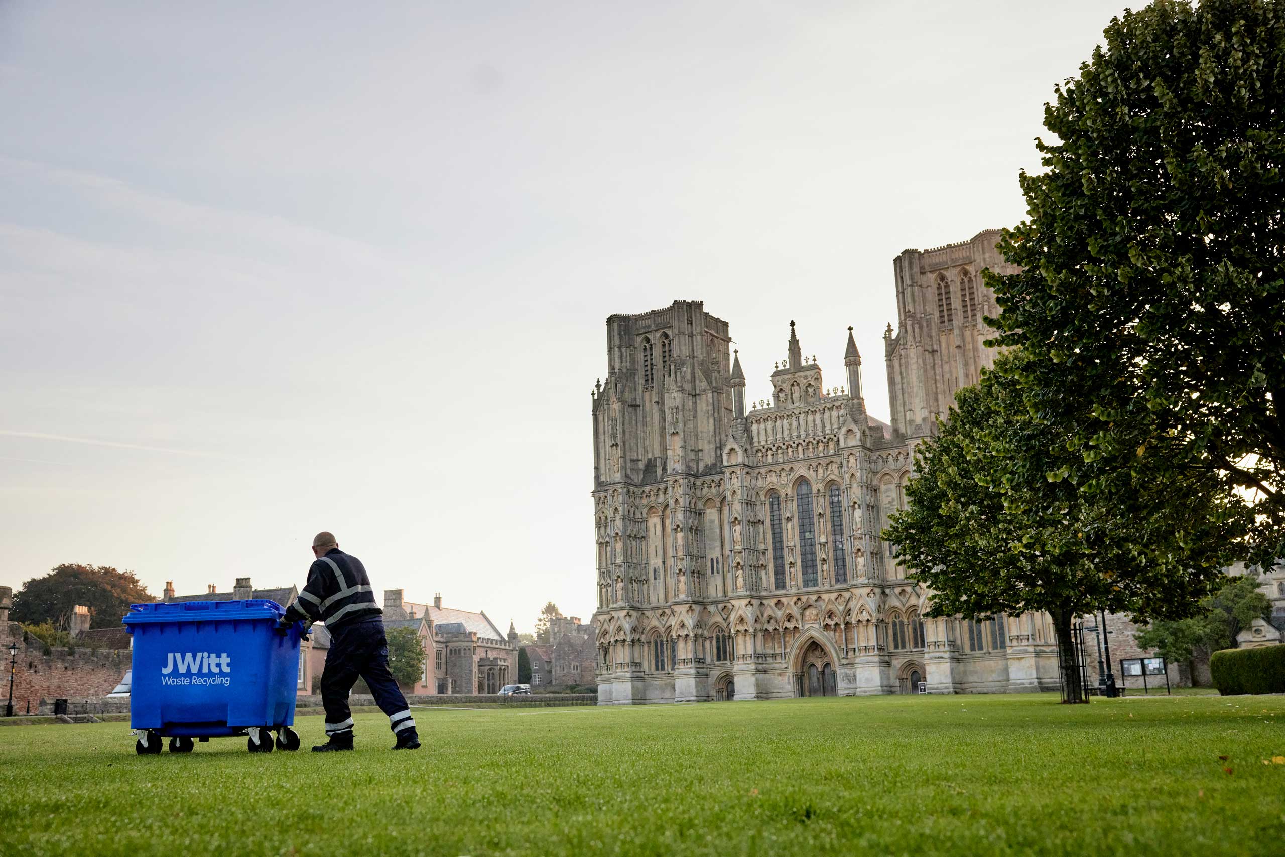 Wells cathedral in the background with a team member collecting a wheelie bin | Wheelie bin hire and collections by JWitt Waste Recycling